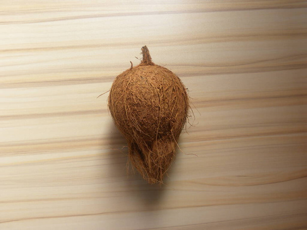Brown color raw whole coconut kept on wooden table - Photo, Image