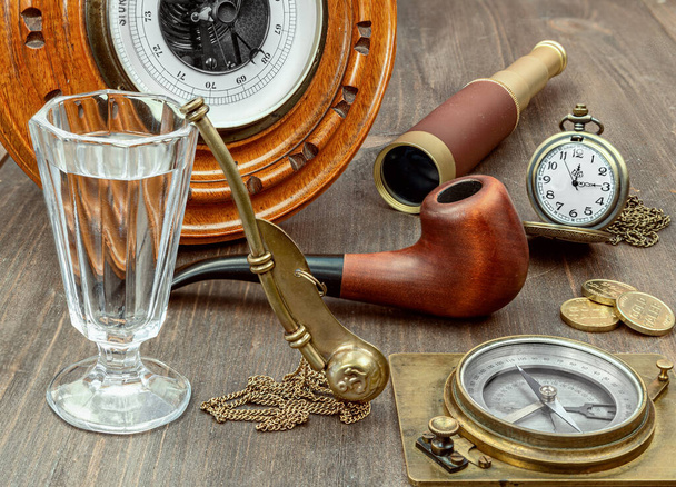 still life of an old boatswain barometer, telescope, compass, glass and boatswain's pipe lying on a wooden table - Photo, image