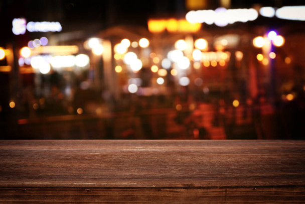 background Image of wooden table in front of abstract blurred restaurant lights - Foto, imagen