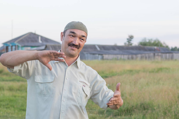 Muslimi vanhempi mies puhuu jotain hauskaa taustaa vasten Siperian kylä, Venäjä - Valokuva, kuva