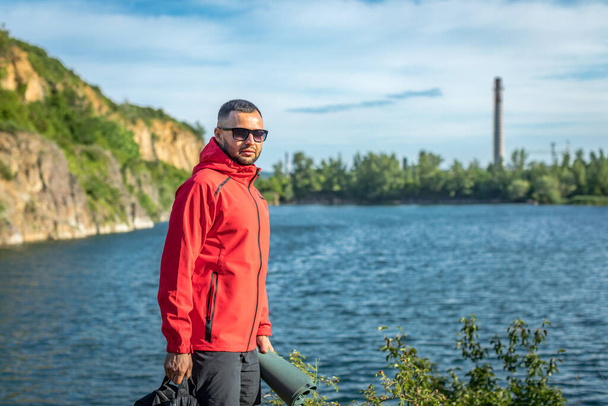 Photo of handsome smiling man in red coat in autumn or spring scenery at the quarry lake. - Foto, Bild