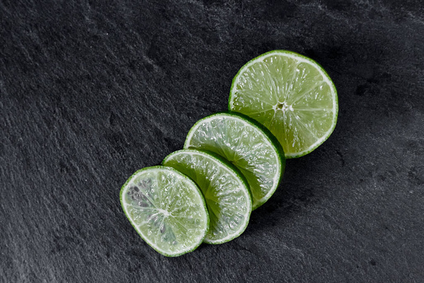 Lime background. The slices of lime on a stone base. On a stone table. Free space for text . The view from the top - Foto, imagen