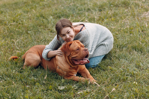 Dogue de Bordeaux or French Mastiff with young woman at outdoor park meadow - Photo, Image