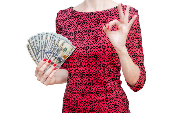 Žena v červených šatech drží peníze a ukazuje gesto OK. Izolované na bílém. - Fotografie, Obrázek
