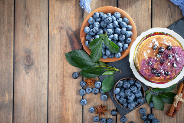 Blueberries in a plate and pancakes, on an old background. - Foto, afbeelding