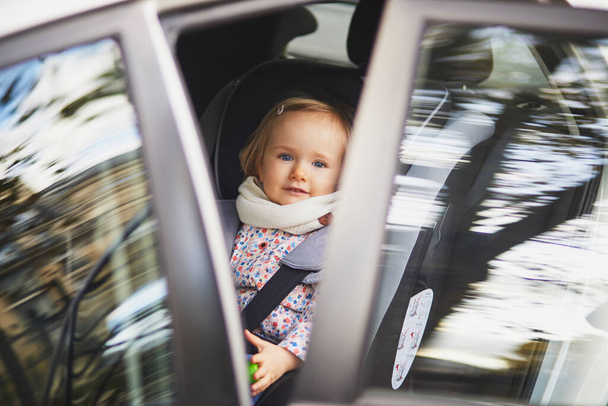 Adorable toddler girl in modern car seat. Little kid traveling by car. Child safety on the road. Trip with a baby - Foto, Bild