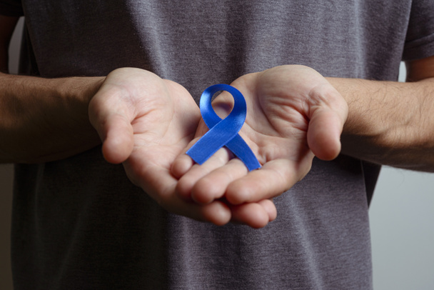 Man holding dark blue ribbon. Awareness ribbon. - Фото, зображення