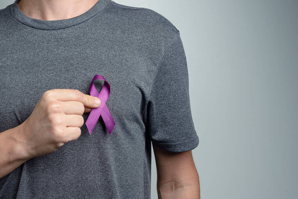 Mann zieht violette Schleife über sein Hemd. Bewusstseinssymbol. - Foto, Bild