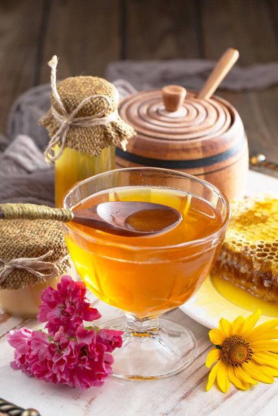 Μέλισσα μέλι σε ένα βάζο με ένα λουλούδι, στο παλιό φόντο. - Φωτογραφία, εικόνα