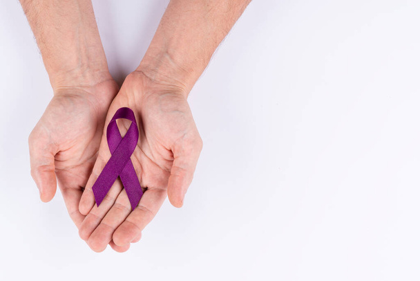 Hands holding purple ribbon. White background. - Zdjęcie, obraz