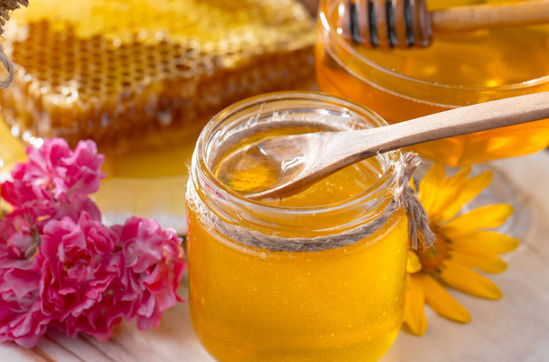 Bee honey in a jar with a flower, on the old background. - Фото, зображення