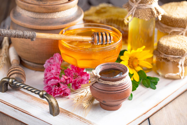Bee honey in a jar with a flower, on the old background. - Photo, Image