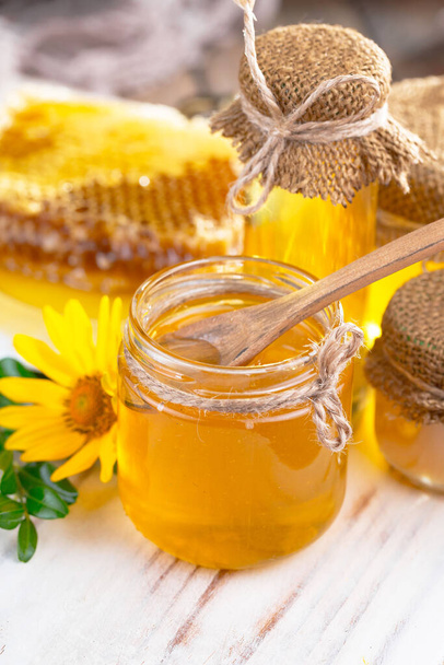 Bee honey in a jar with a flower, on the old background. - Foto, Bild