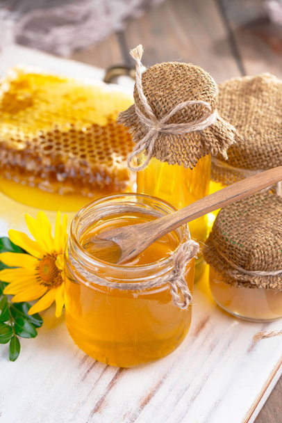 Bee honey in a jar with a flower, on the old background. - Foto, Imagen