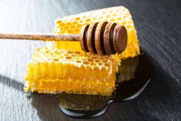 La miel fluye lentamente desde el palo hacia el panal. - Foto, imagen