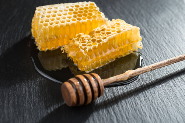 Miel de abeja en un frasco con una flor, sobre el fondo viejo. - Foto, imagen
