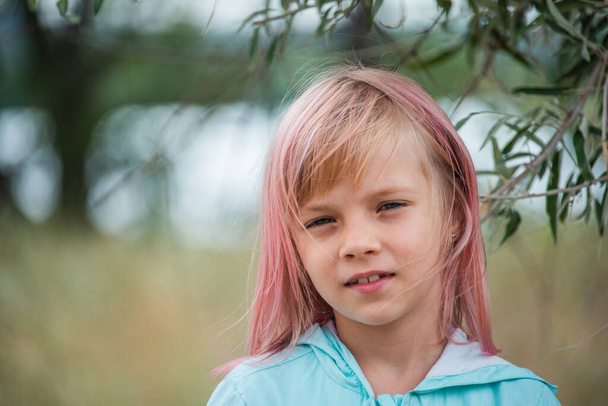ładny portret dziewczynki dziecka. Odkryty portret uroczej dziewczynki w letni dzień. Portret dziewczynki z różowymi włosami. Dziecko w wieku 6-7 lat - Zdjęcie, obraz