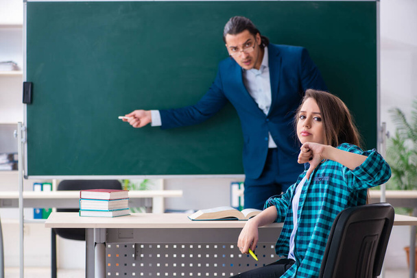Young handsome teacher and female student in the classroom - Foto, afbeelding