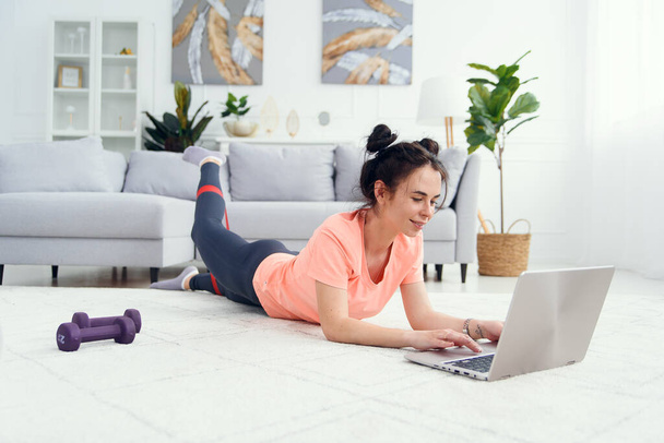 Young pretty woman trains online with elastic bands for fitness. Beautiful woman does stretching exercises at home. - Fotoğraf, Görsel