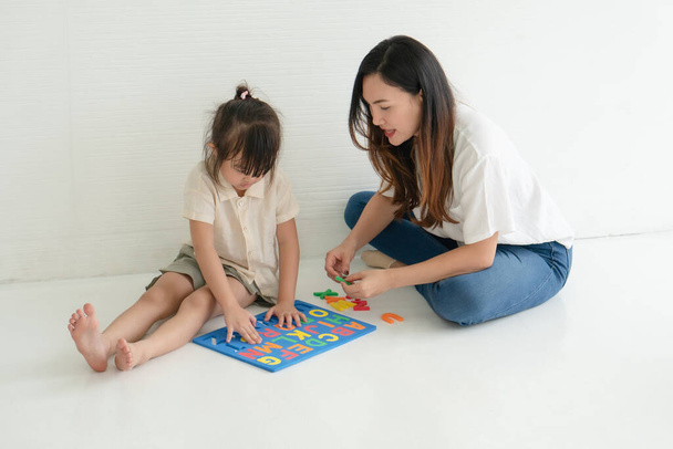 Asijská matka učí svou malou dceru hrát doma abecední hádanky. domácí a rodinná výchova spolu koncept - Fotografie, Obrázek