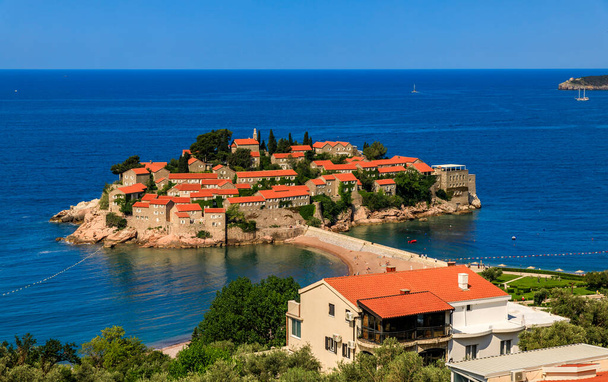Karadağ 'ın Budva kenti yakınlarındaki Adriyatik deniz kıyısındaki Sveti Stefan lüks tatil köyünün resimli manzarası - Fotoğraf, Görsel