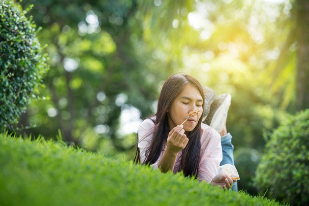 Relax beautiful asian woman smiling face Lying down on green grass field in outdoors garden park enjoy nature morning. Freedom Lifestyle woman breathing fresh air in green park on spring lawn outdoors - Zdjęcie, obraz