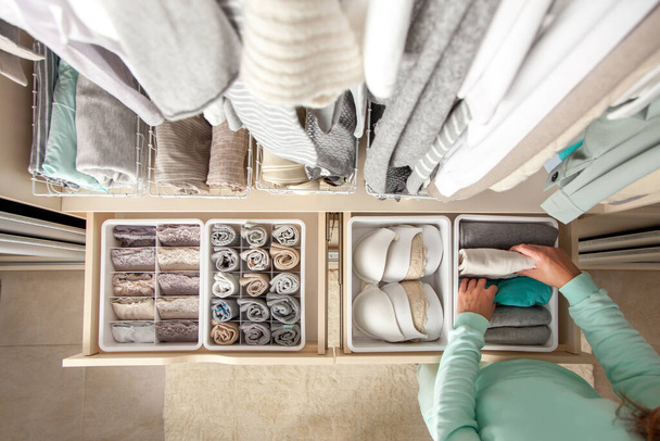 Unidentified neat housewife puts container with socks and pantyhose on wardrobe drawer during general cleaning by modern storage system. Concept of beautiful and comfortable organization - Foto, Imagem