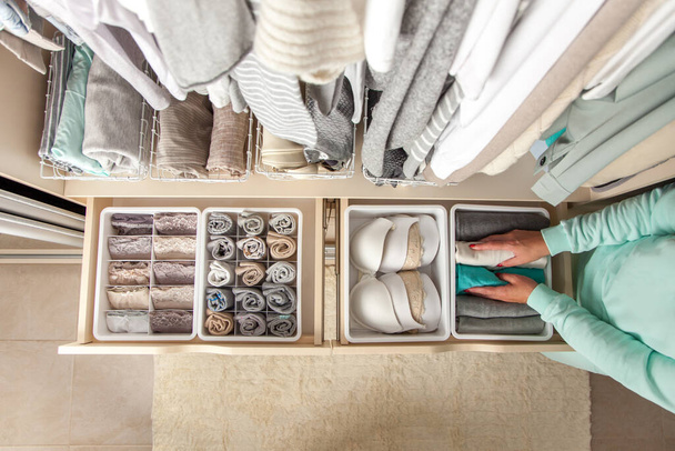 Unidentified neat housewife puts container with socks and pantyhose on wardrobe drawer during general cleaning by modern storage system. Concept of beautiful and comfortable organization - Fotografie, Obrázek