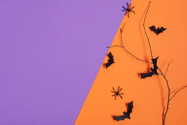 Halloween decorations, paper bats flying on tree branch and spiders on purple and orange background. Halloween background. - Photo, Image