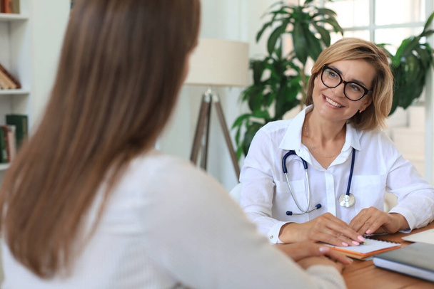 Middle aged female doctor therapist in consultation with patient in office - Foto, imagen