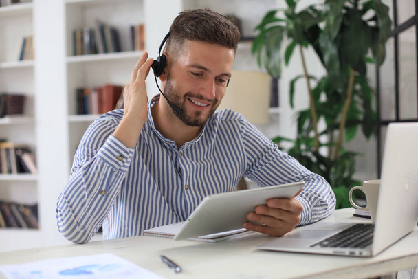 Confident man wearing headset speaking and watching business webinar training, listening to lecture - Фото, зображення