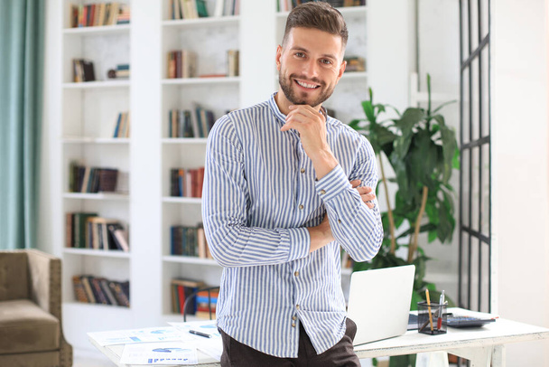 Portrait of happy businessman with arms crossed standing in office - Foto, Bild