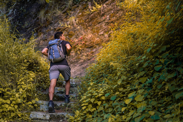 Un joven escalando la montaña con una mochila. Trekking y aventura. - Foto, Imagen