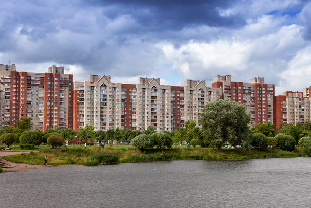 Saint Petersburg, Russia, June 13, 2020.  Beautiful pond in the large park. Multi-storey modern residential buildings in a distance - 写真・画像