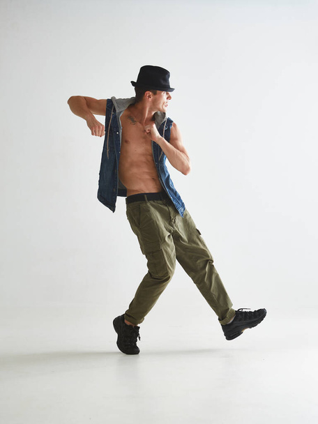 Cool young man breakdancer in hat dancing hip-hop in studio isolated on white background - Foto, Bild