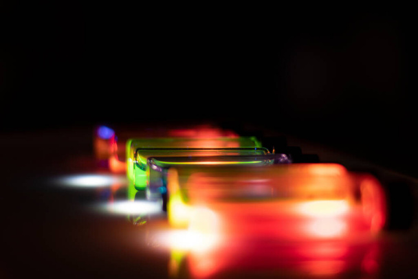 Varios reactivos coloridos sobre la luz UV en un laboratorio de química para el experimento de atención médica para el desarrollo de medicamentos - Foto, Imagen