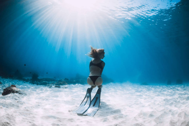 Mujer liberadora posando sobre fondo arenoso con aletas. Freediving en el océano azul en las islas de Hawaii - Foto, imagen