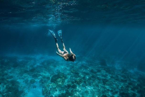 Vrouwenvrije duiker met vinnen zwemmen onder water in transparante oceaan - Foto, afbeelding