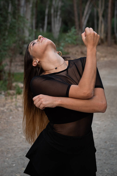 Νεαρή όμορφη σύγχρονη χορεύτρια και χορογράφος χορεύουν σε εξωτερικούς χώρους στο δάσος. Γυναίκα που χορεύει στο περιβάλλον. - Φωτογραφία, εικόνα