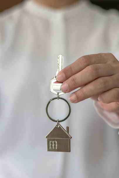 House key in real estate sale person, landlord or home Insurance broker agent's hand giving to buyer customer for new family owner, property assurance concept - Photo, Image