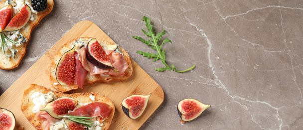 Bruschettas with cheese, prosciutto and figs on marble table, top view. Space for text, banner design  - Fotoğraf, Görsel