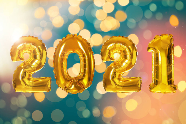 2021 New Year celebration. Bright gold balloons and blurred lights on color background - Фото, зображення