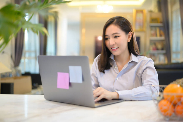 A beautiful Asian business woman is working with her computer at home , Telecommunication , social distancing ,Work from home concept . - Фото, зображення