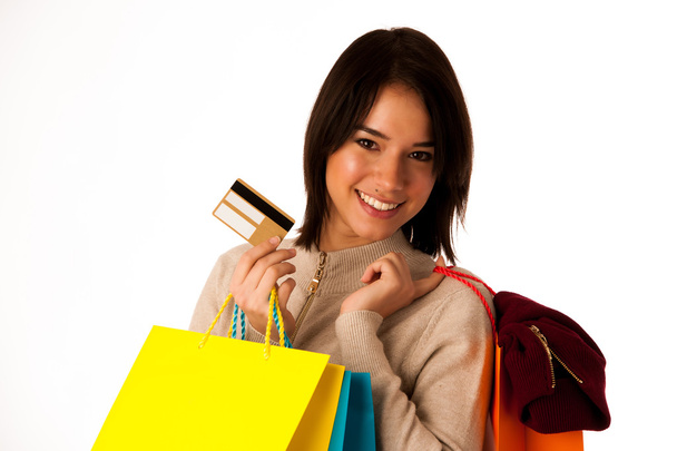 Atractiva mujer caucásica asiática con bolsas de compras y tarjeta de crédito en sus manos aisladas sobre fondo blanco
 - Foto, imagen