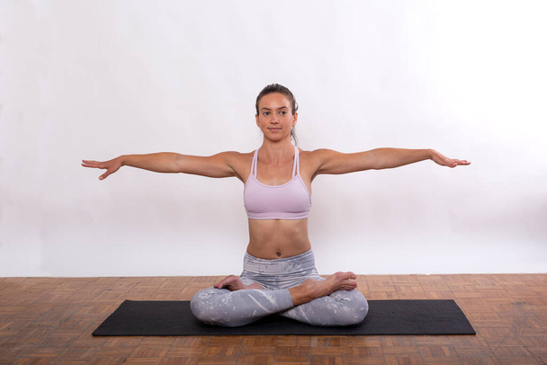 Jovencita en casa estudio ejercicio yoga con cuerpo flexible haciendo figuras delante de fondo blanco
 - Foto, imagen
