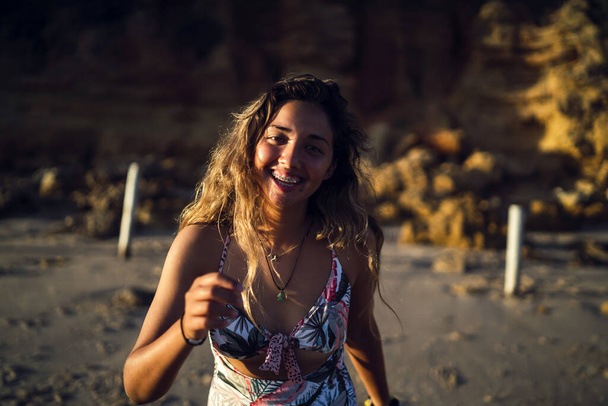 Eine schöne Frau posiert im Badeanzug vor dem Hintergrund einer Klippe - Foto, Bild