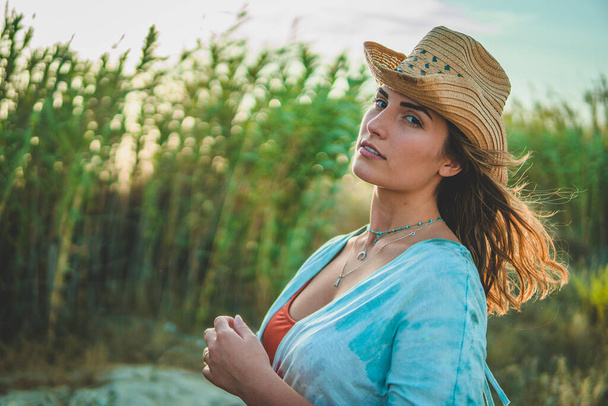 A shallow focus shot of a European female with a cowboy hat on the beach - Fotó, kép
