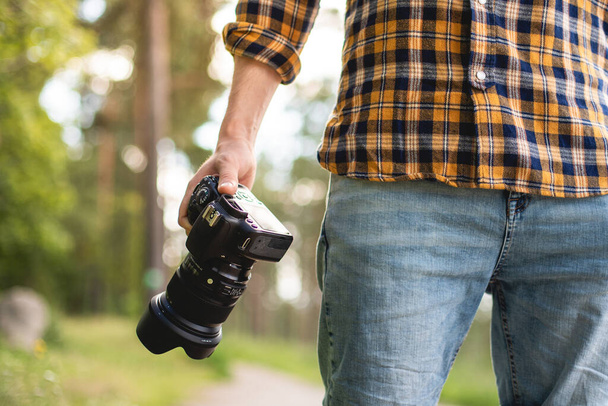 A photographer holding a camera in a park getting ready to take photos - Zdjęcie, obraz