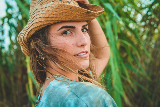 A shallow focus shot of a European female with a cowboy hat on the beach - 写真・画像