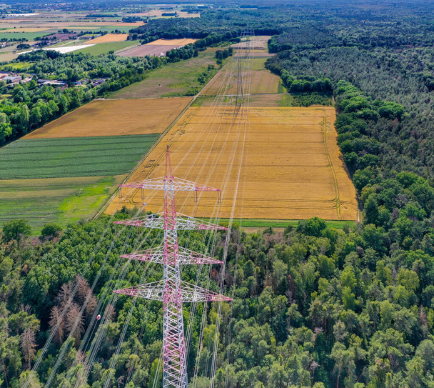 Orman bölgesinde metal elektrik direkleriyle ve Almanya 'da yüksek voltajlı kablolarla çalışan bir elektrik hattı boyunca varsayılan hava görüntüsü - Fotoğraf, Görsel